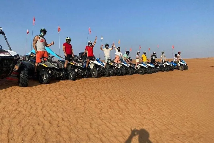 Un grupo de personas posando con quads en las dunas del desierto.